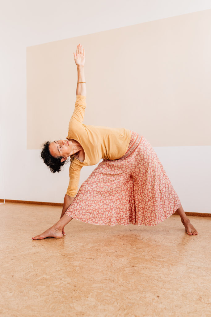 Die Yogalehrerin Maria Lichtenberg verweilt im ausgestreckten Dreieck/ utthita-trikonasana (von vorn fotografiert) in ihrem Yogaraum in Leipzig.