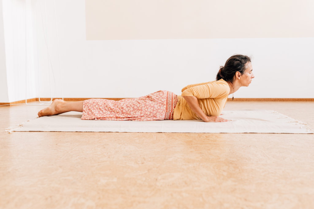 Die Yogalehrerin Maria Lichtenberg verweilt in der Kobrahaltung - der Oberkörper geht aus der Kraft des unteren Rückens in eine Rückbeuge in ihrem Yogaraum in Leipzig.