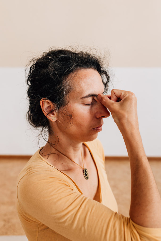 Die Yogalehrerin Maria Lichtenberg hält Daumen, Ringfinger und kleinen Finger an der Nasenwurzel als Vorbereitung für die Atempraxis in ihrem Yogaraum in Leipzig.