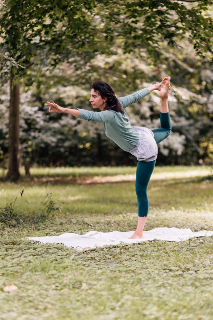 Die Yogalehrerin Maria Lichtenberg geht in die Haltung des Tänzers/ Naṭa-rājāsana in der freien Natur (in der Nähe ihres Yogaraumes in Leipzig).