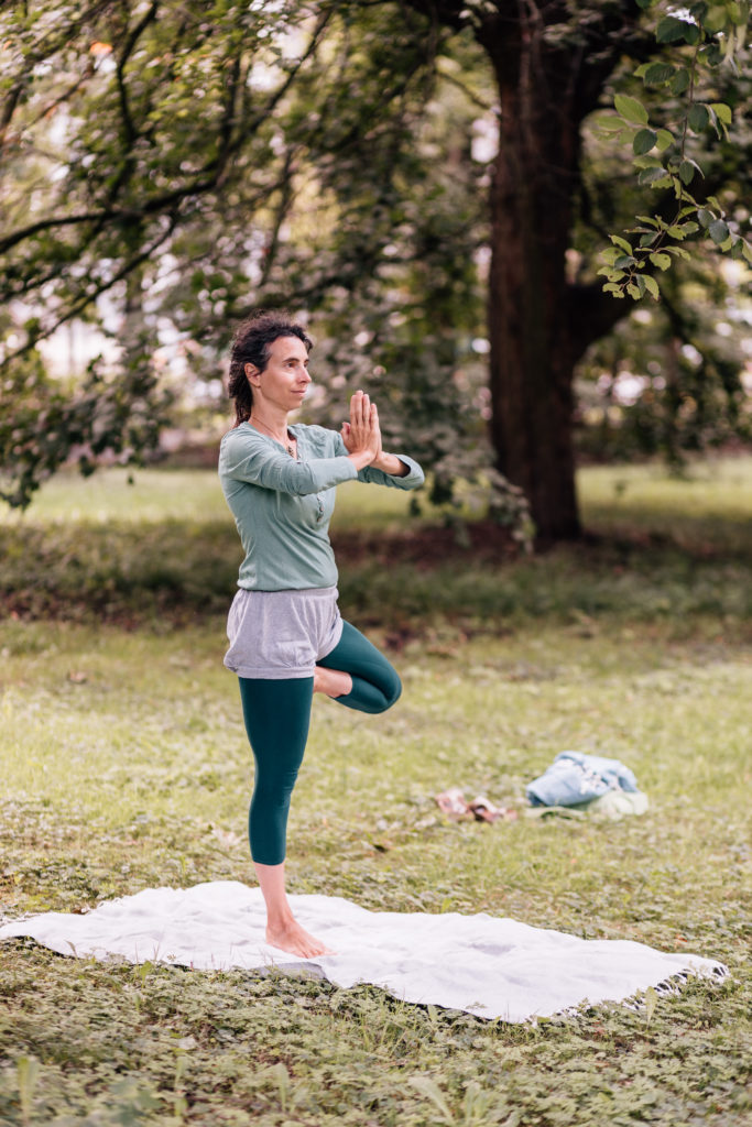 Die Yogalehrerin Maria Lichtenberg praktiziert inmitten von Bäumen die Baumhaltung/ Vṛkṣāsana in der freien Natur (in der Nähe ihres Yogaraumes in Leipzig).