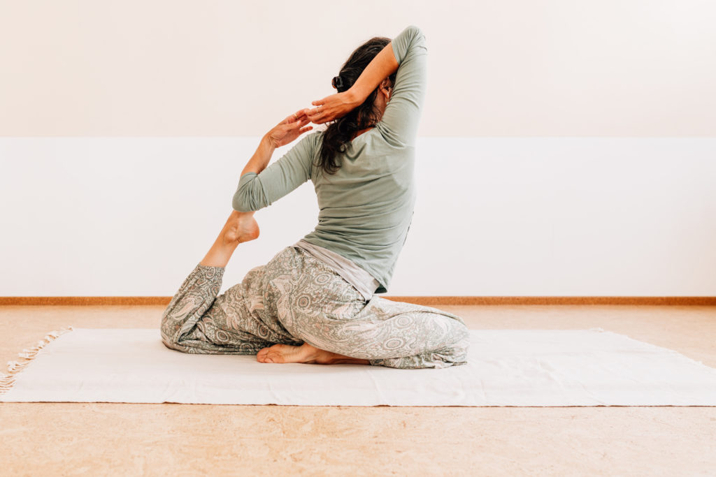 Die Yogalehrerin Maria Lichtenberg verweilt in der eleganten Haltung der Taube in ihrem Yogaraum in Leipzig.