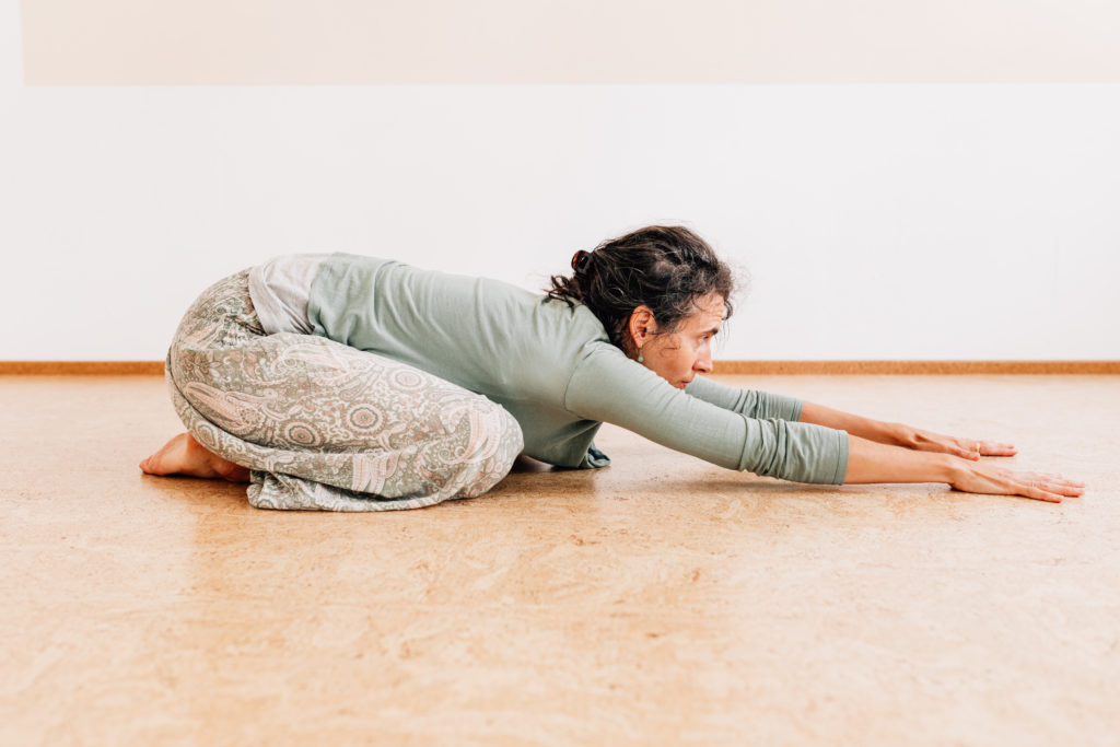 Die Yogalehrerin Maria Lichtenberg verlängert den Oberkörper als Vorbereitung für die Haltung des herabschauenden Hundes in ihrem Yogaraum in Leipzig.