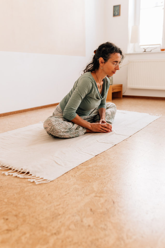 Die Yogalehrerin Maria Lichtenberg verlängert im Sitzen ihre Wirbelsäule nach diagonal oben in ihrem Yogaraum in Leipzig.