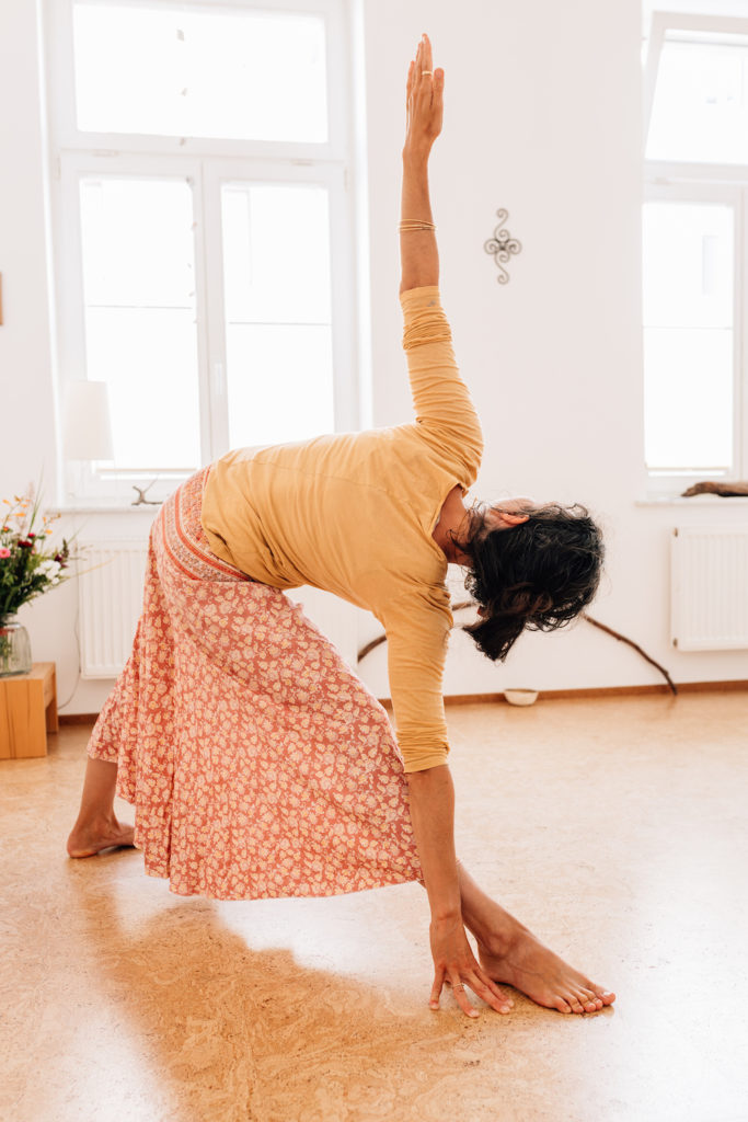 Die Yogalehrerin Maria Lichtenberg praktiziert das ausgestreckte Dreieck/ utthita-trikonasana (von hinten fotografiert) in ihrem Yogaraum in Leipzig.