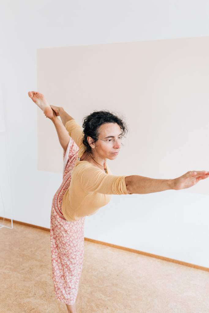 Die Yogalehrerin Maria Lichtenberg verweilt in der Haltung des Tänzers/ Naṭa-rājāsana - der Oberkörper befindet sich in eine Rückbeuge, die Balance hält sie auf einem Bein in ihrem Yogaraum in Leipzig.