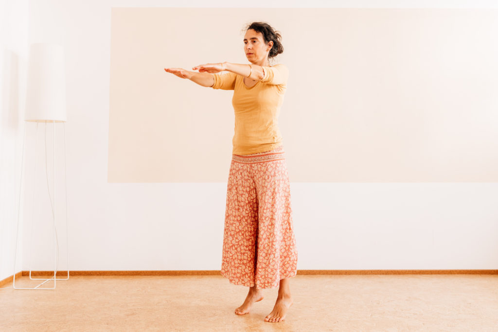 Die Yogalehrerin Maria Lichtenberg begibt sich einatmend mit nach vorn ausgestreckten Armen auf die Zehenspitzen und hält dort die Balance  in ihrem Yogaraum in Leipzig.